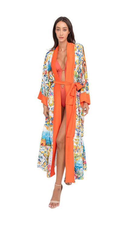 Model wearing an orange CAPRI Long Robe with belt over a swimsuit, adorned with a colorful floral pattern.